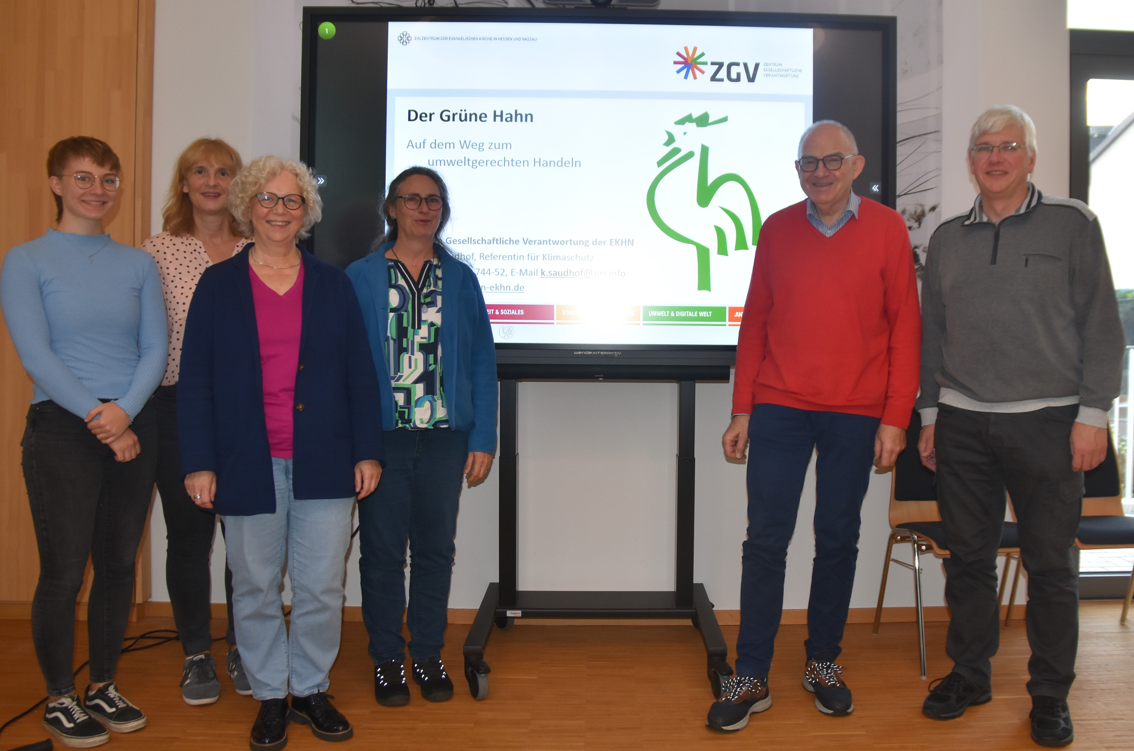 Umweltteam, Präses Rolf Hartmann und stellvertretender Dekan Ulrich Bauersfeld präsentieren den Grünen Hahn, bildlich dargestellt auf der Videowand.