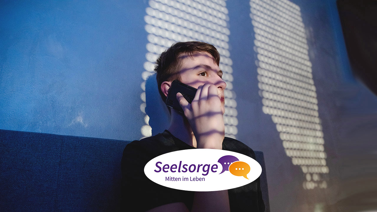 Telefonseelsorge Ein junger Mann telefoniert im Dunklen