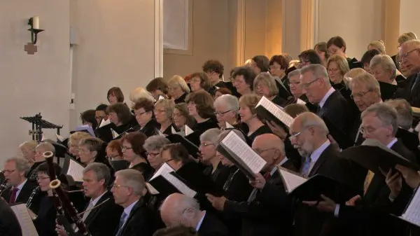 Oratorienchor_Bergstraße_C_Michaelsgemeinde_16zu9.jpg Ein großer gemischter Chor singt in einer Kirche von gestaffelten Emporen, begleitet von Bläsern und mit geöffneten Notenmappen.