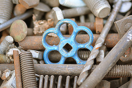 viele Schrauben, eine blaues Wasserhahn-Handrad in der Mitte
