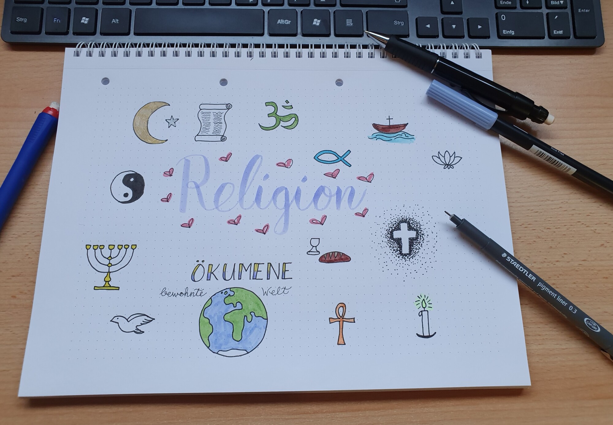 Auf einen Zeichenblock gemalte Symbole der Weltreligionen