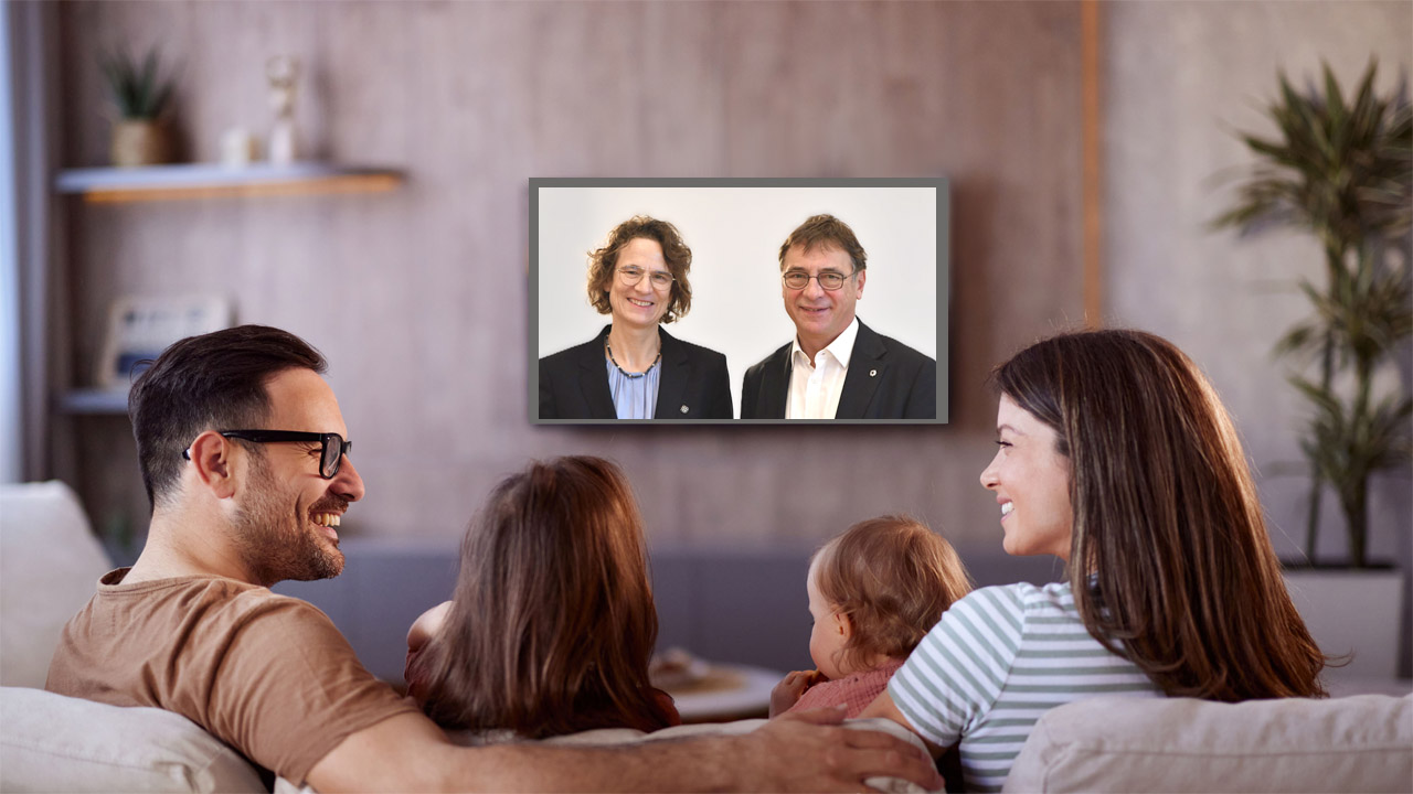 Eine Familie vor dem Fernsehbildschirm, auf dem Volker Jung und Christiane Tietz zu sehen sind