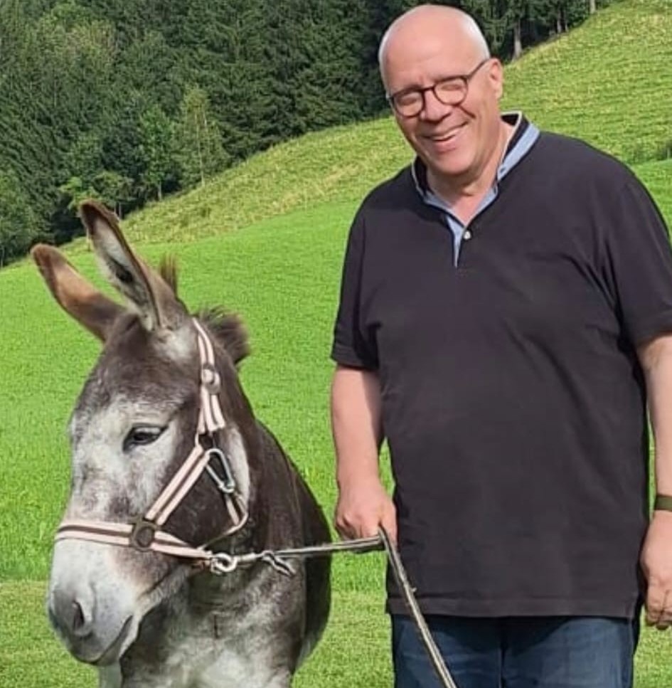 Mann und Esel auf einer Wiese