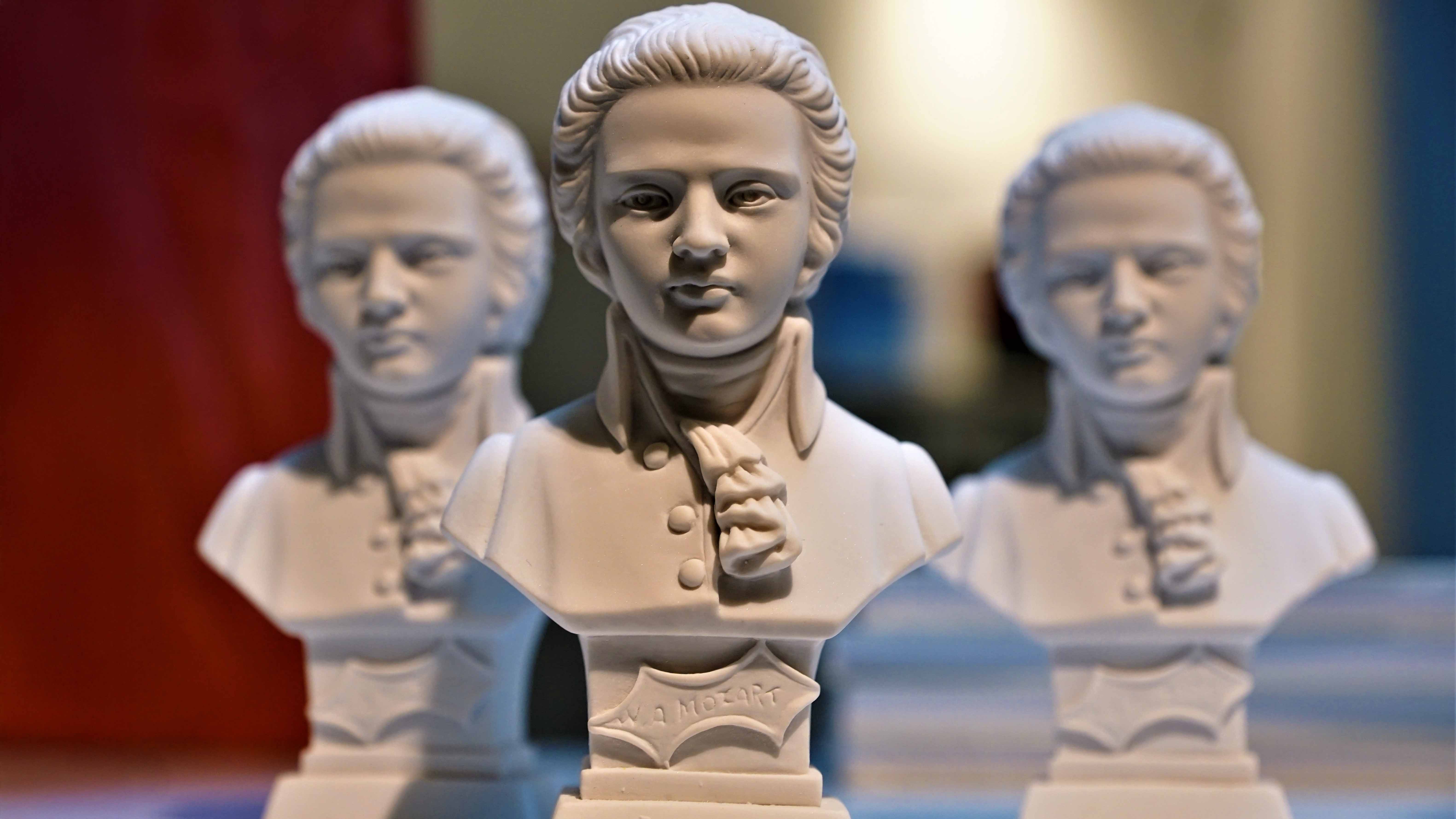 Drei weiße Mozart-Büsten stehen nebeneinander, die mittlere ist scharf im Fokus, die beiden anderen sind unscharf im Hintergrund.