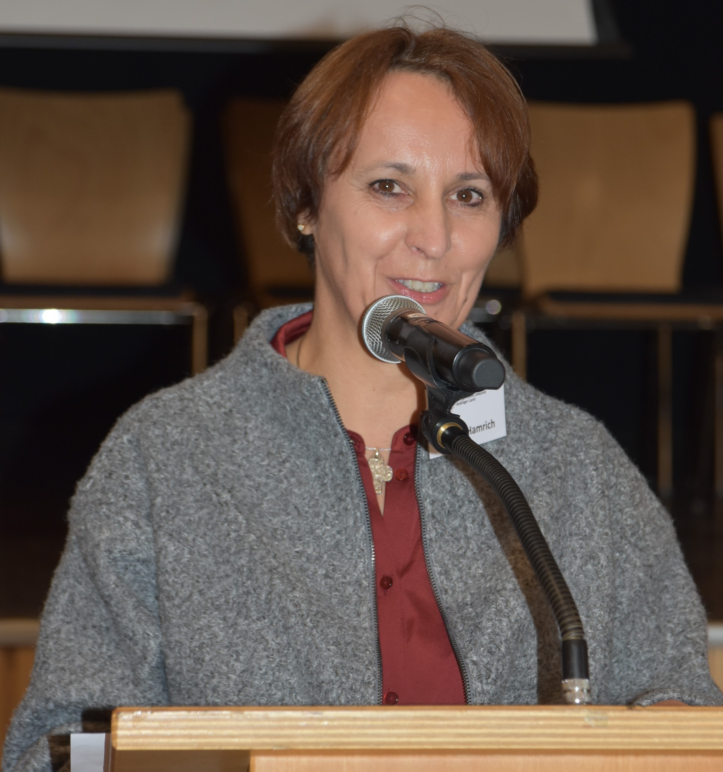 Dekanin Birgit Hamrich, rote Bluse, graue Jacke, an einem Rednerpult im Bürgerhaus Nidda.