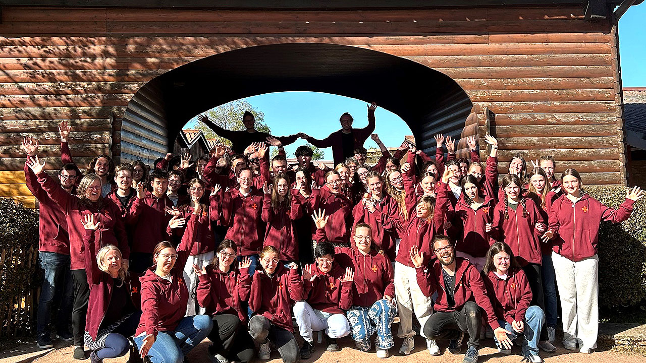 Gruppenbild mit Jugendlichen in bordeauxfarbenem Sweatshirt