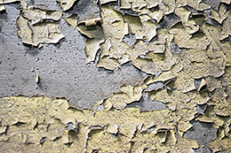 Abplatzungen von Lack auf einer rauen Oberfläche.