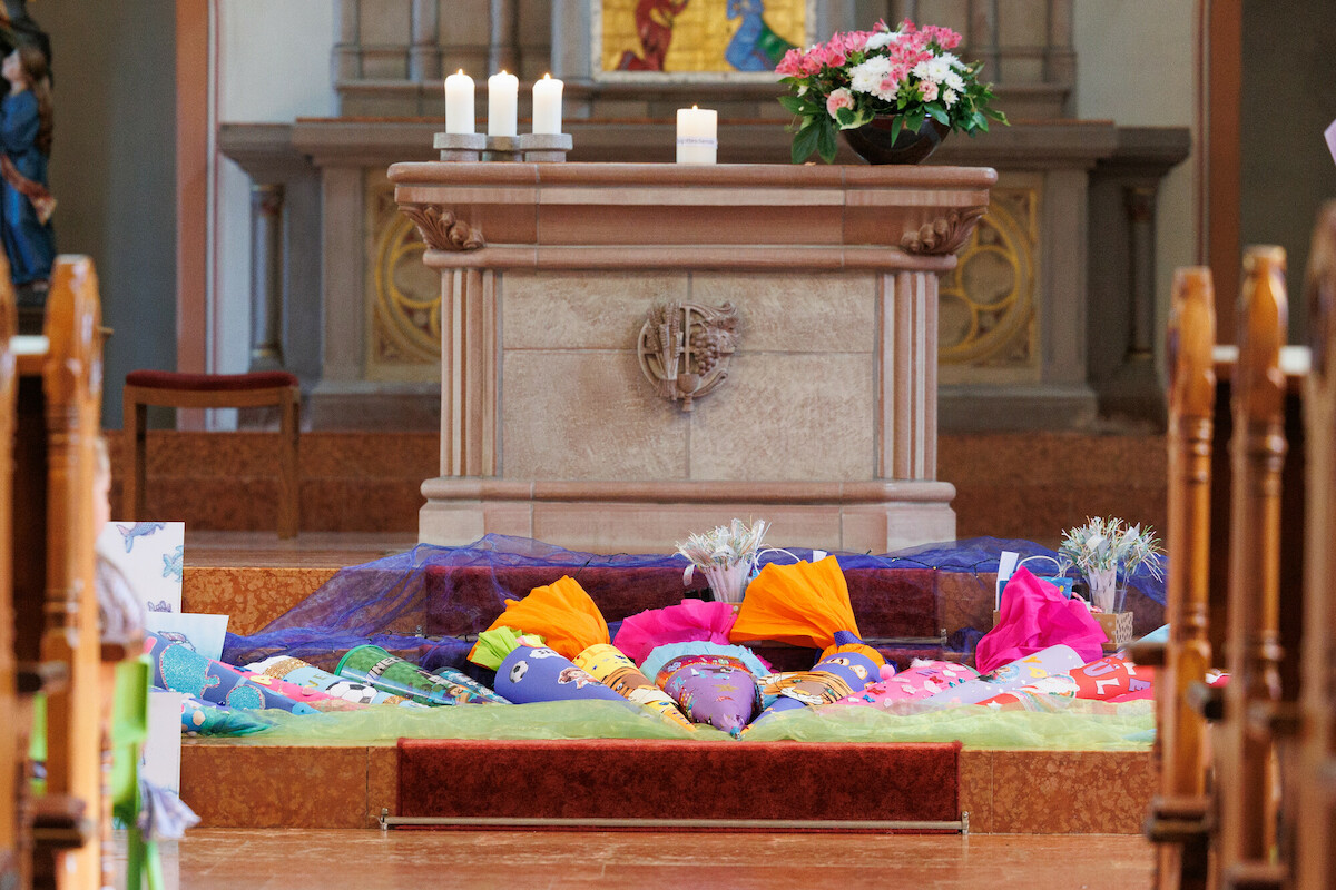 Schultüten liegen im Halbkreis vor einem Altar.