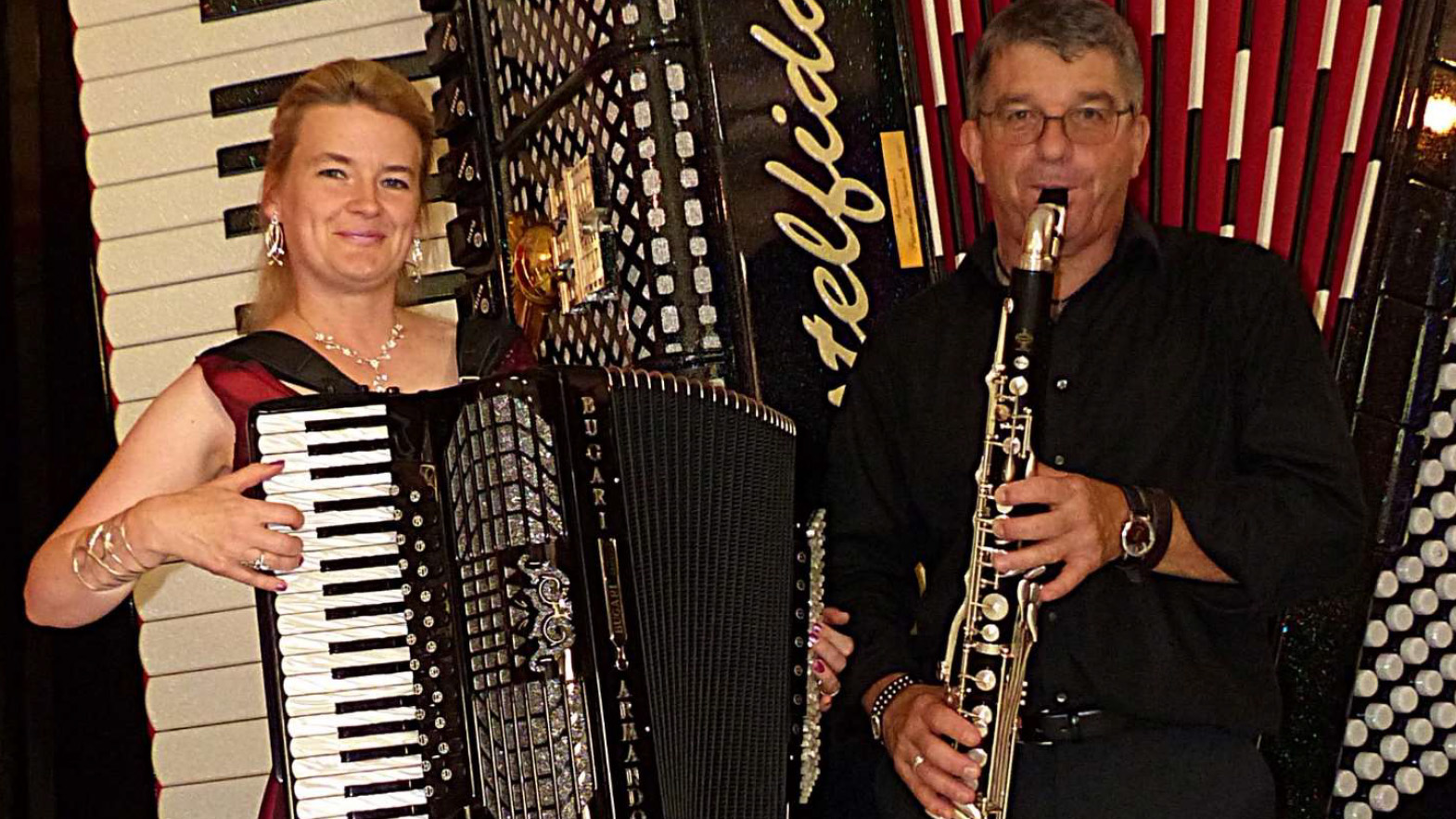 Duo Sing Your Soul C Veranstalter 16zu9.jpg Eine Frau spielt Akkordeon, während ein Mann neben ihr Klarinette spielt. Im Hintergrund sind weitere Akkordeons zu sehen.