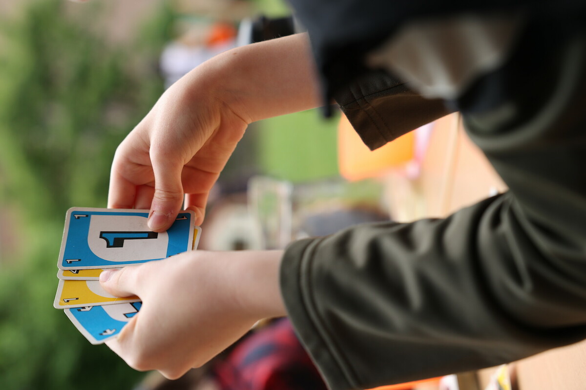 Kinder und Erwachsene spielen, sprechen, essen miteinander, draußen im Gemeindegarten