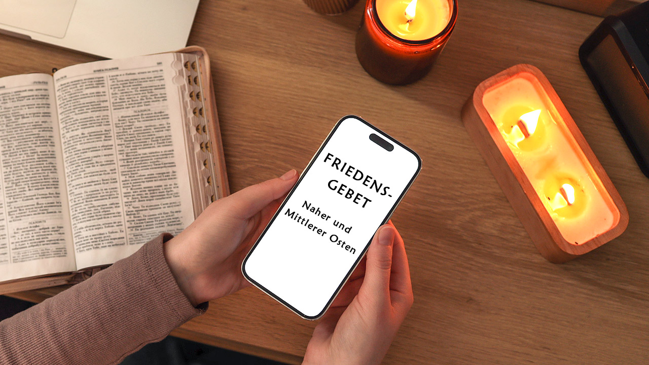 Friedengebet Kerzen, Laptop und Smartphone, auf dem "Friedensgebet - Naher und Mittlerer Osten " steht