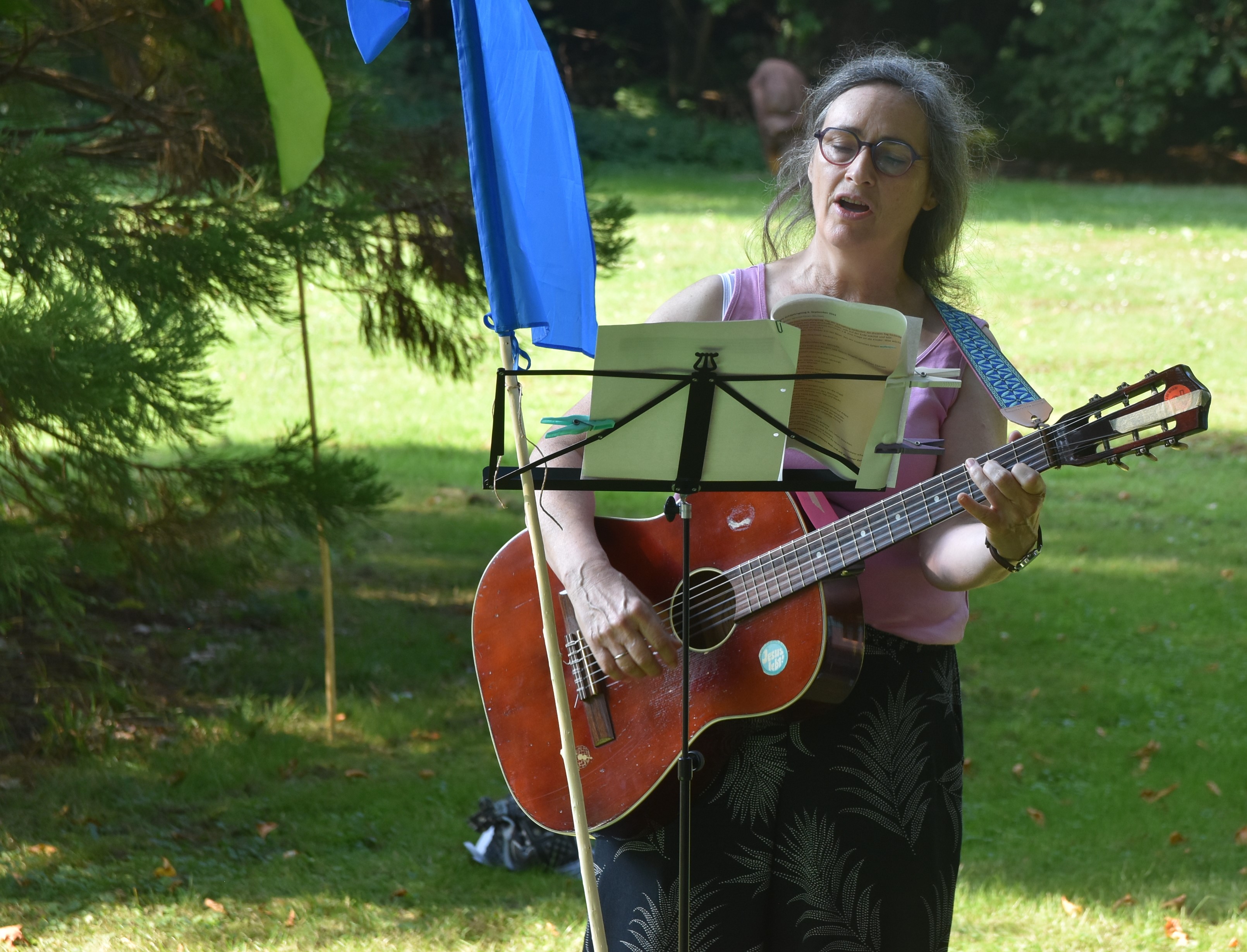 Ruth Weyel-Bietz steht mit einer Gitarre im Kurpark Bad Salzhausen und singe.