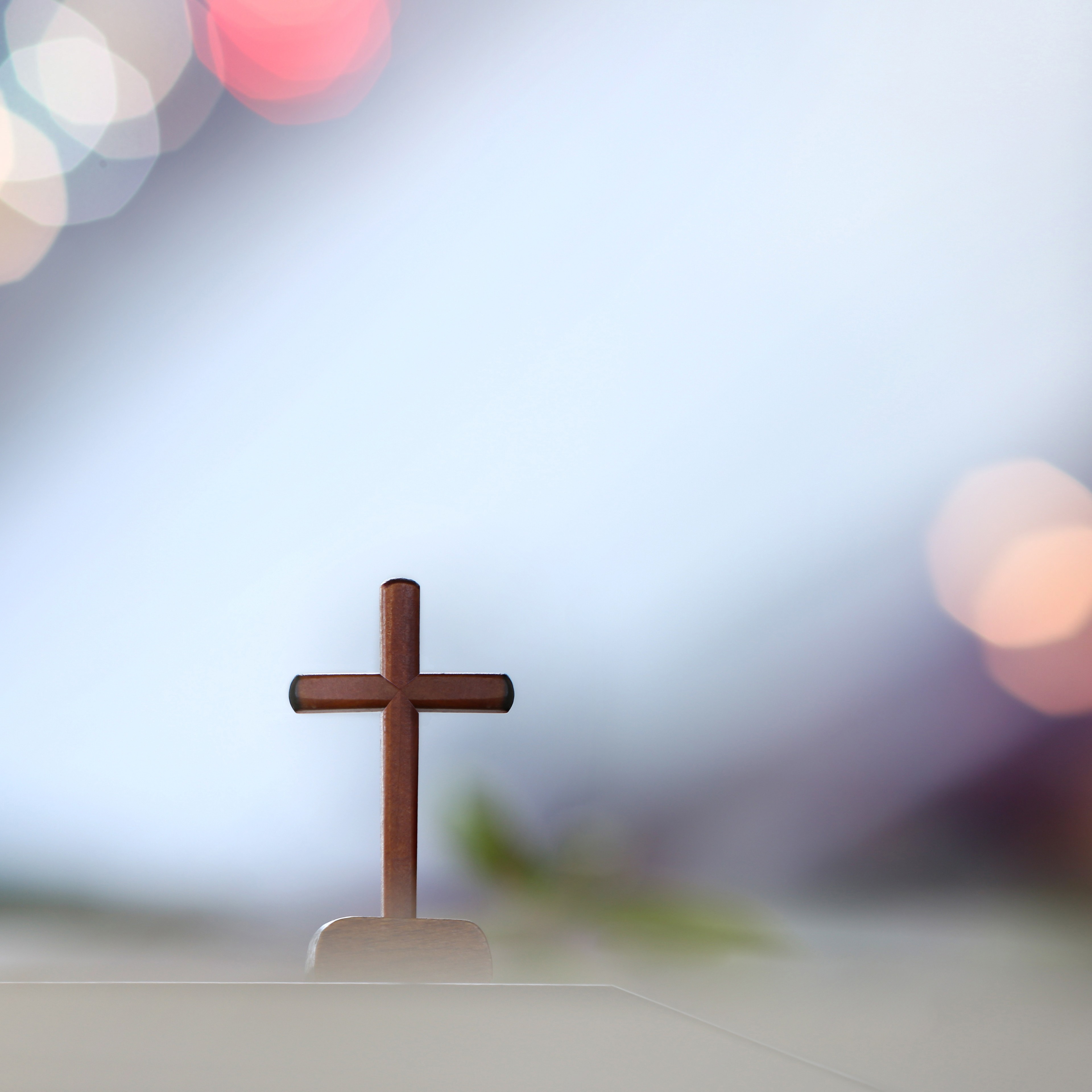 Ein Holzkreuz vor einem hellen Hintergrund mit Lichtreflexen