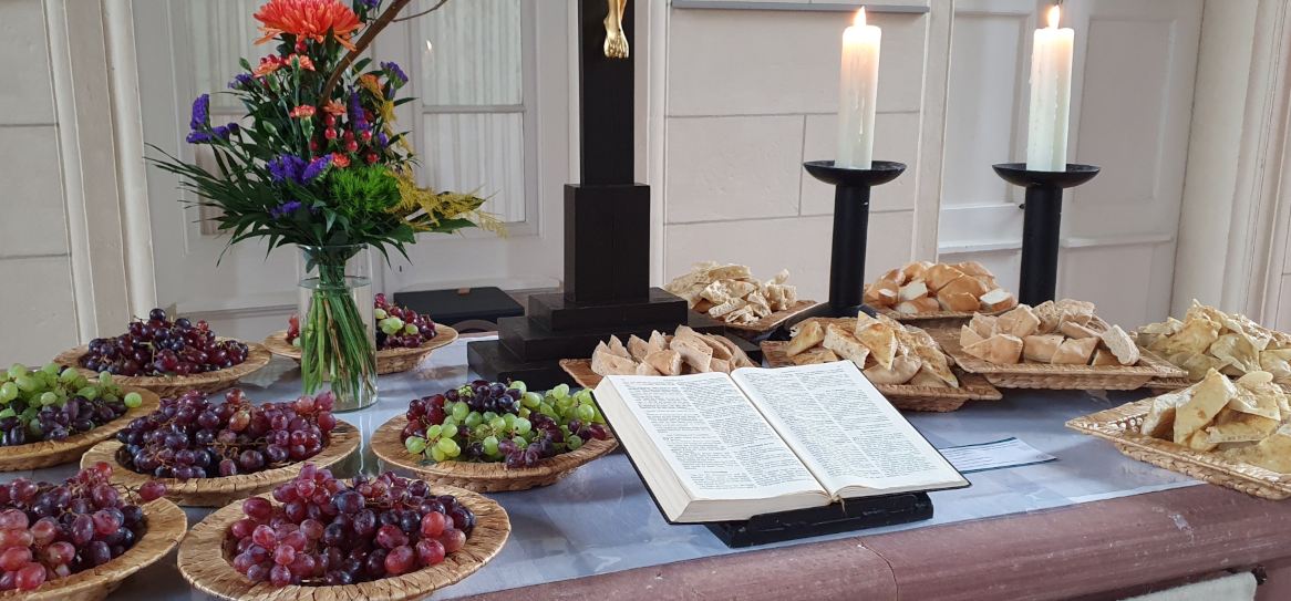 Es sind Brotkörbe und Trauben auf dem Altar zu sehen.