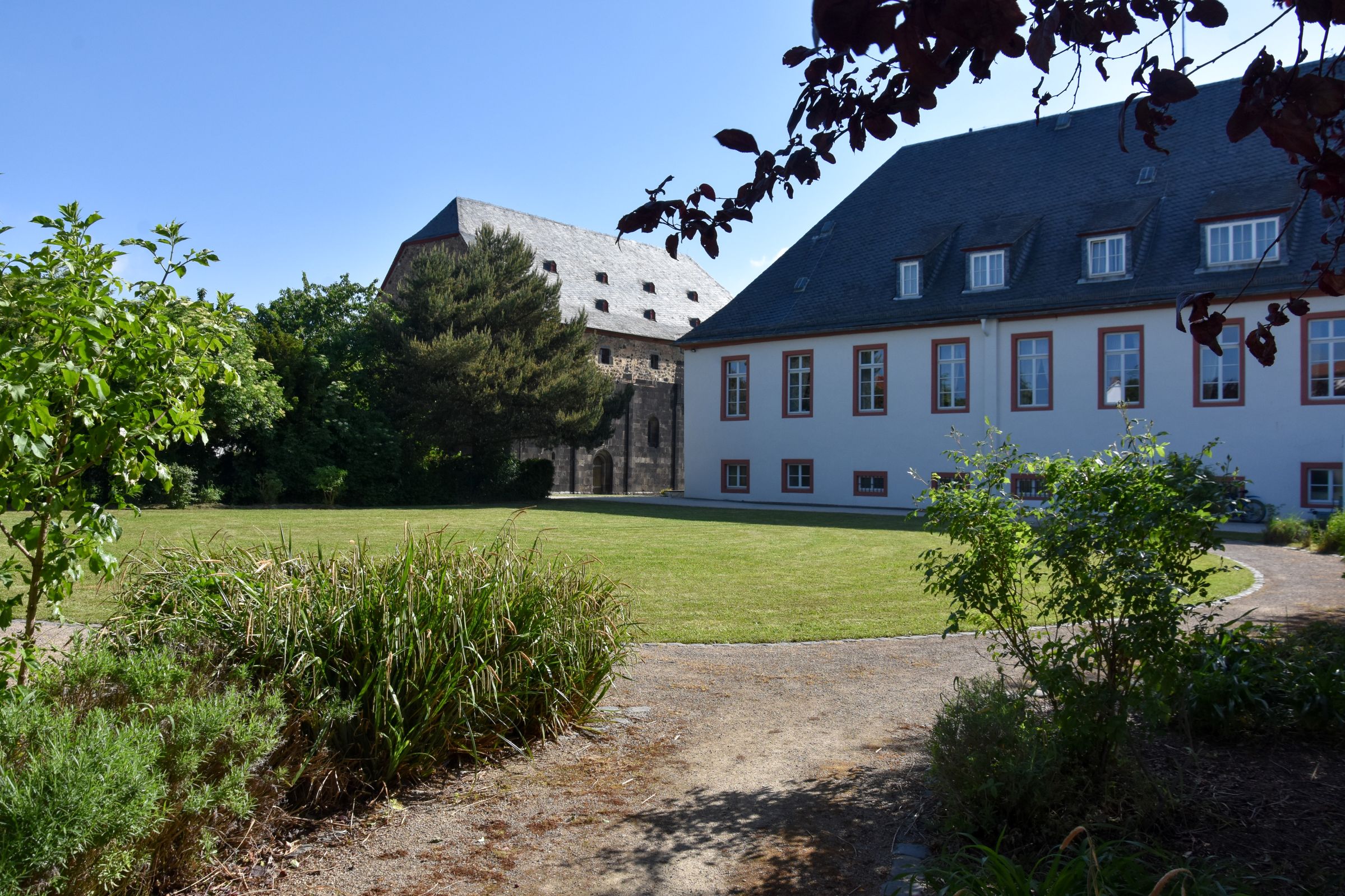 Geistliches Zentrum Kirche und Ordenshaus, im Vordergrund Pflanzen und eine grüne Wiese