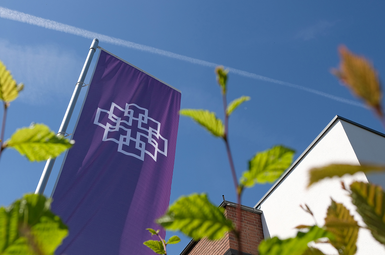 Die lila Fahne mit Facettenkreuz am Haus der Kirche in Bad Soden