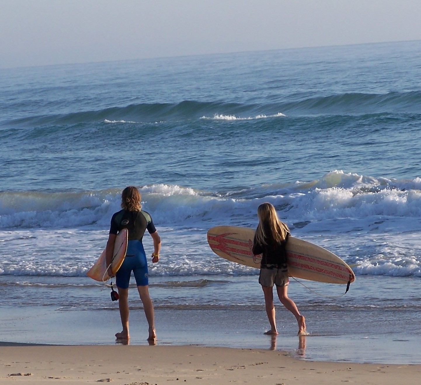 Surfen Zwei Jugendliche sind am Strand mit Surfbrettern unter dem Arm zu sehen
