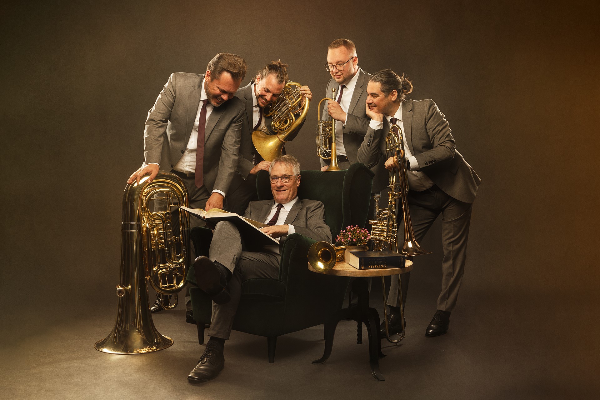 Die Band CLASSIC BRASS posiert fröhlich um einen Sessel herum