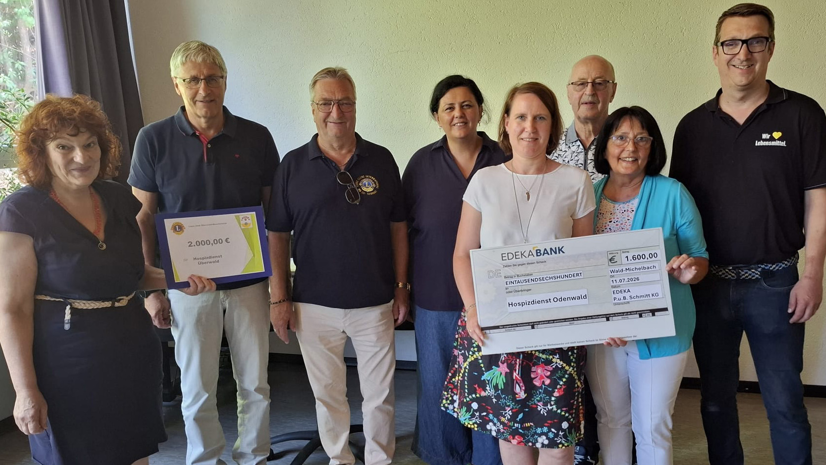 Acht Personen stehen nebeneinander und übergeben zwei Spendenschecks über 2.000 Euro und 1.600 Euro an den Hospizdienst Odenwald.