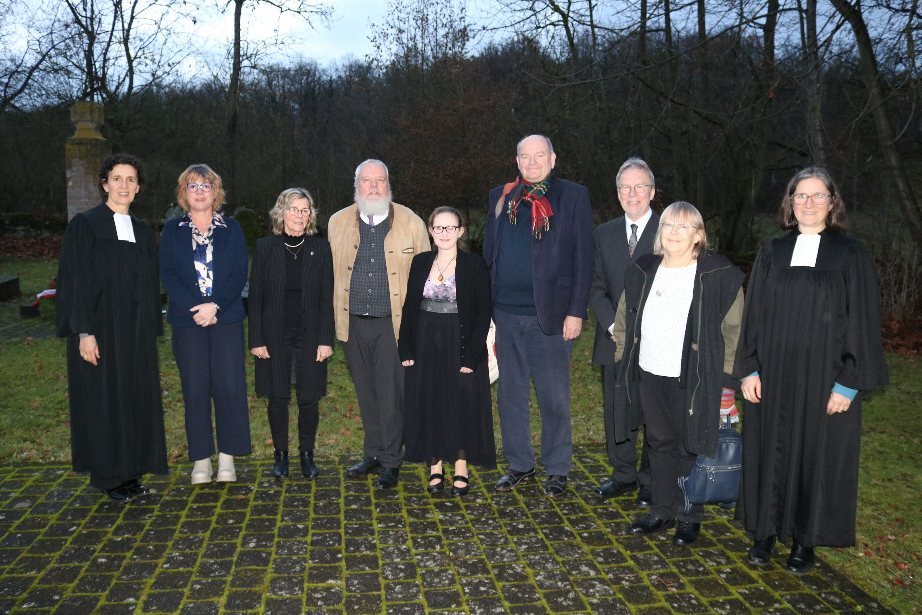 Gruppe von Menschen auf einer Wiese vor einer Kirche