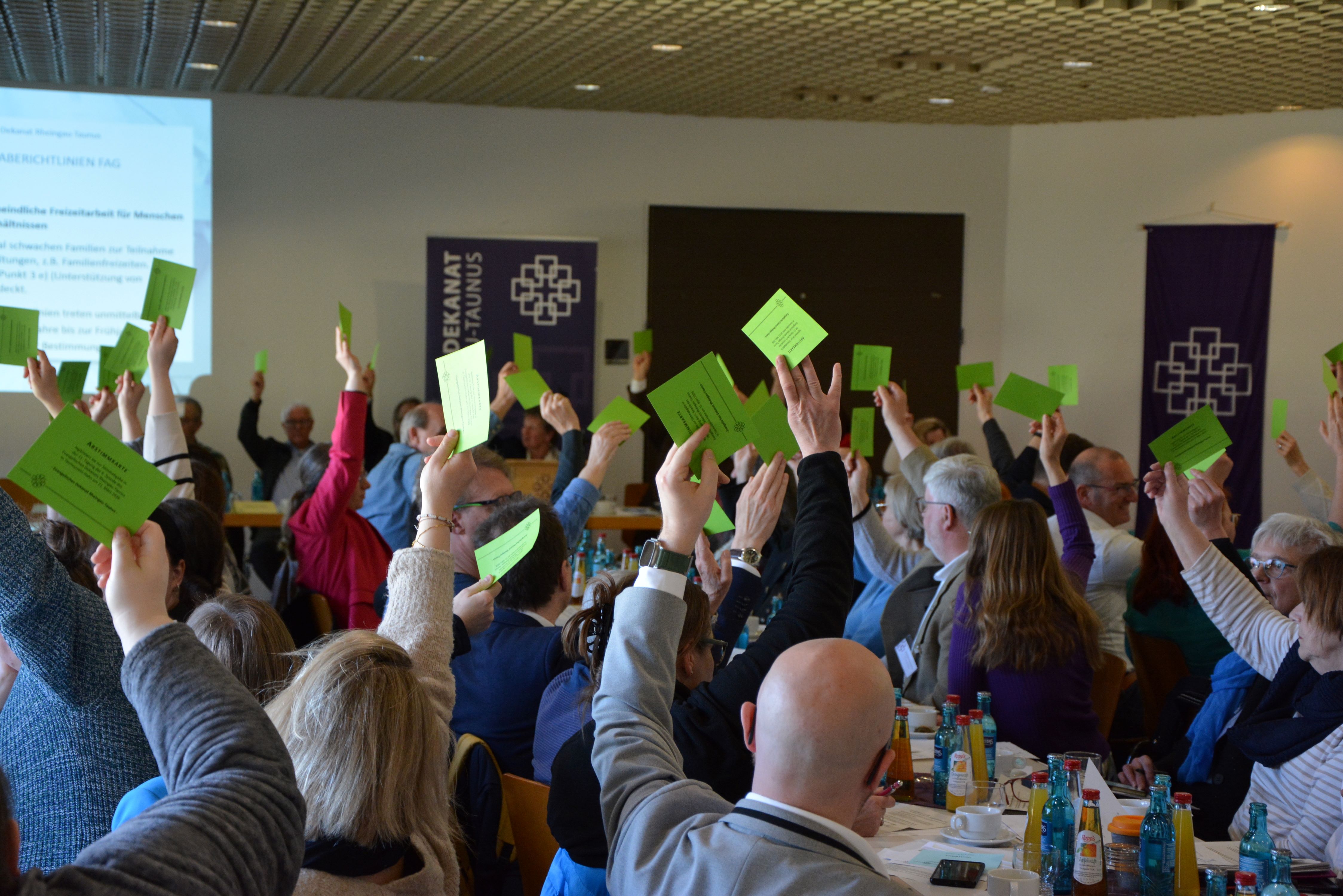 Abstimmung auf einer Dekanatssynode - viele Hände mit grünen Karten sind zu sehen