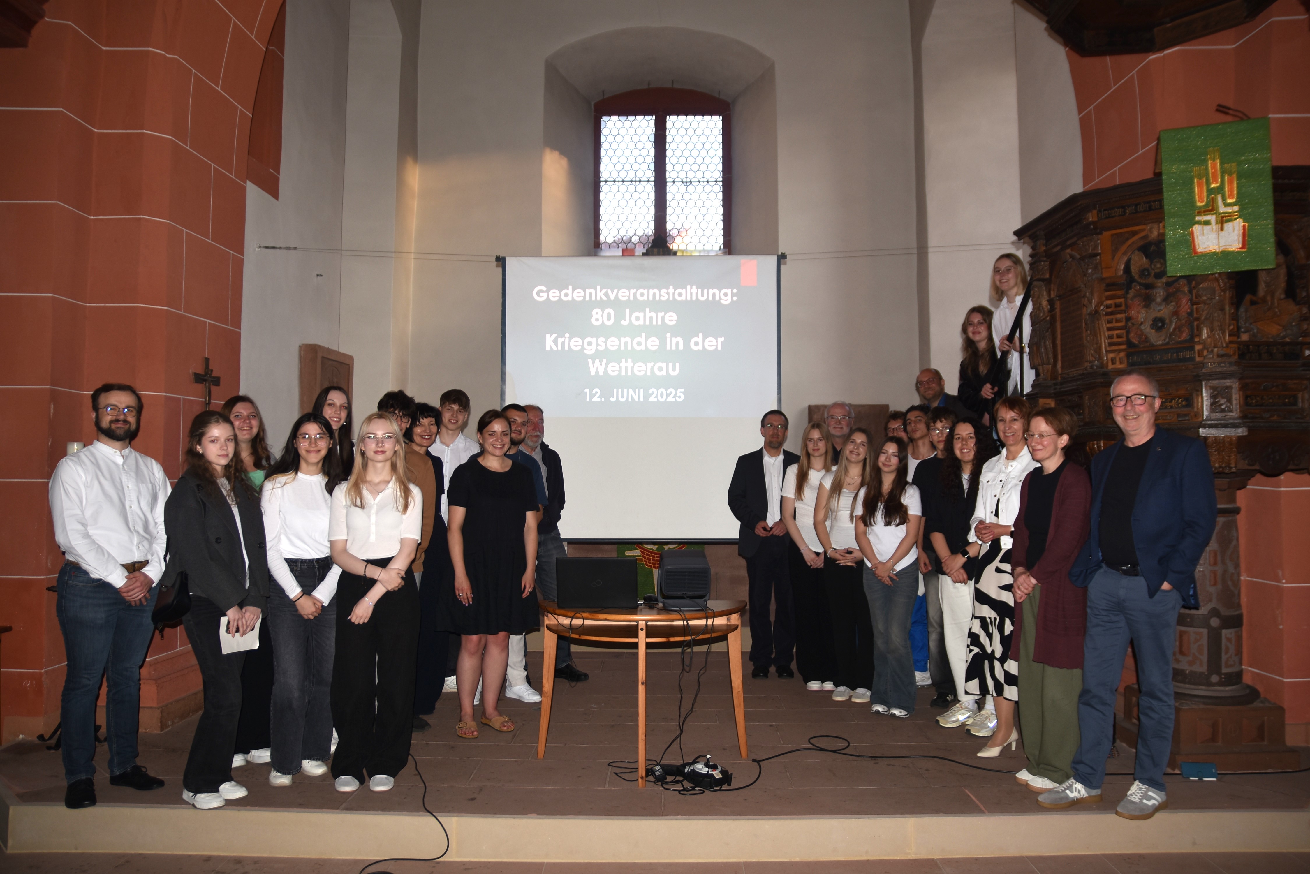Eine große Gruppe Erwachsener und Jugendlicher hat sich im Altarraum der Stadtkirche Nidda zum Foto aufgestellt.