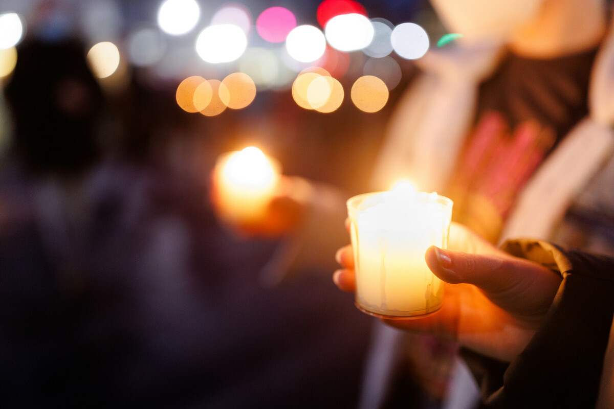 Man sieht eine Gruppe von Menschen auf dem Marktplatz in Selters mit Kerzen in der Hand und  Pfarrerin Swenja Müller, die das Friedensgebet leitet