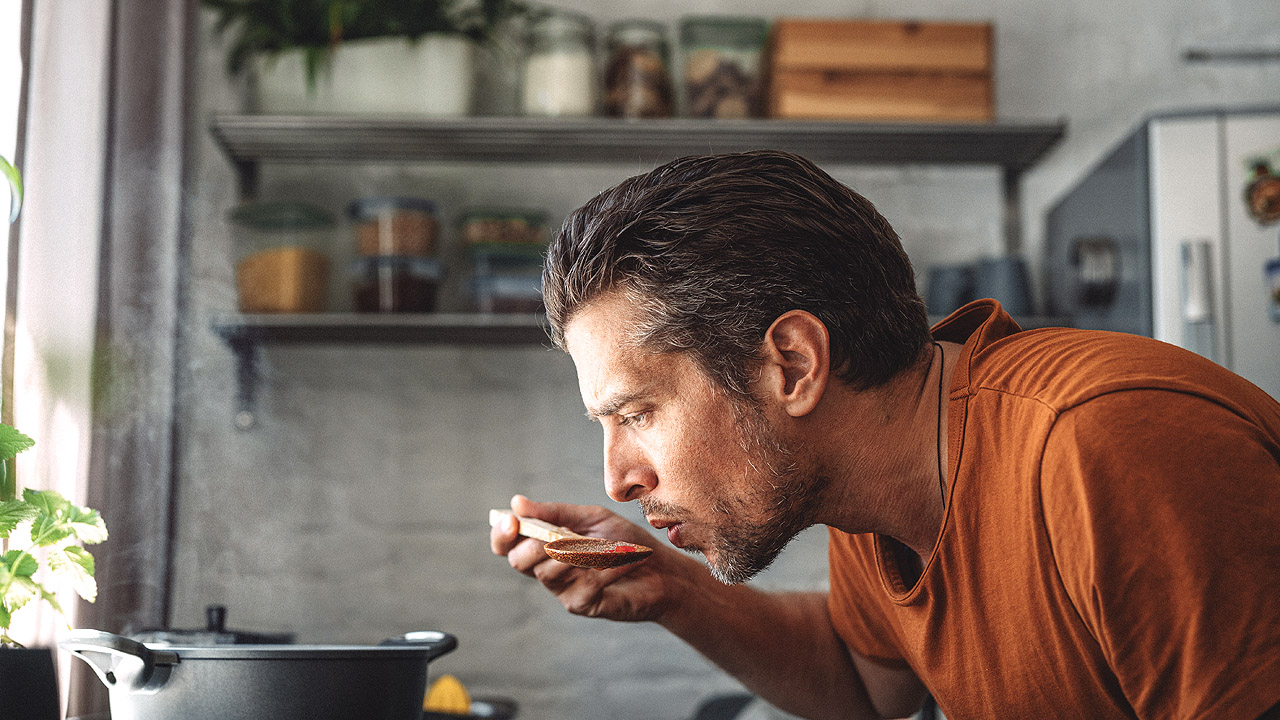 Mann schmeckt ab Mann schmeckt ab beim Kochen