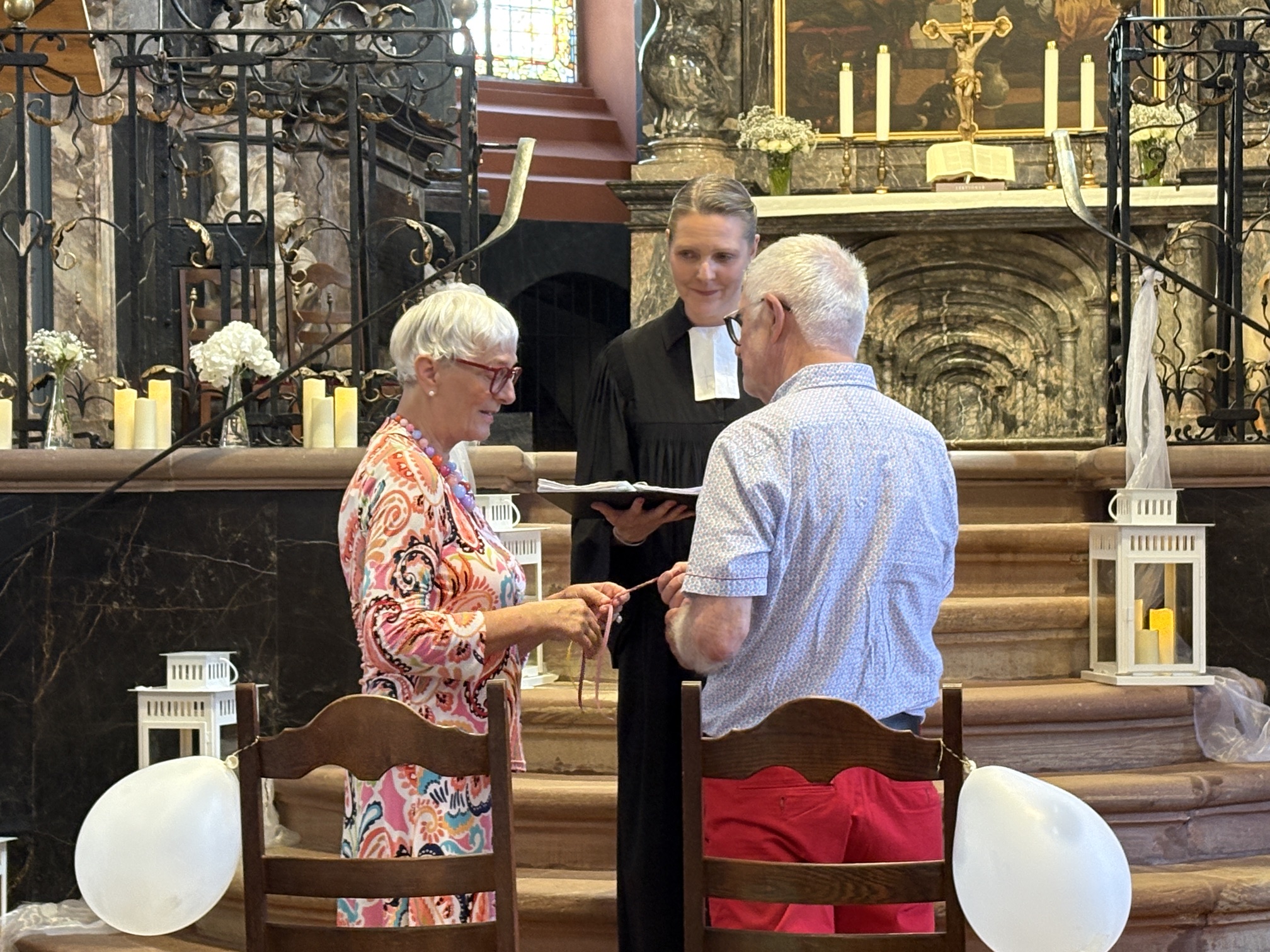 Ein Paar steht in der Unionskirche vor dem Altarraum und flechtet ein Bändchen beim so genannten Segensritual