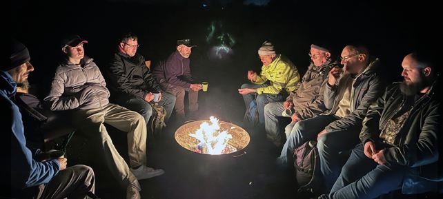 Männer sitzen um ein Lagerfeuer