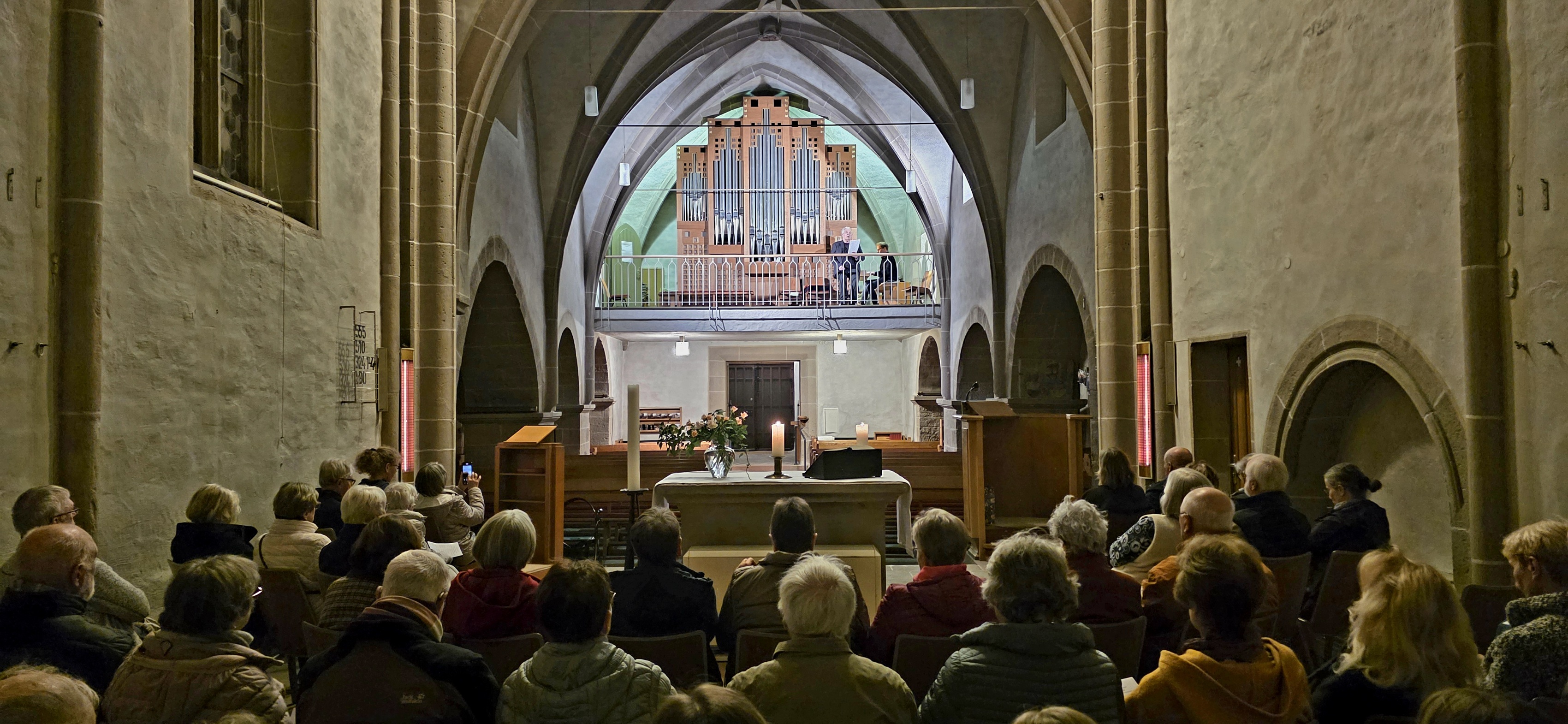 Publikum in Kirche, im Hintergrund eine Orgel und zwei Künstler.