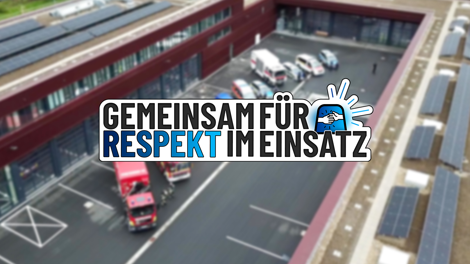 Zu sehen ist die Grafik mit dem Text: Gemeinsam für Respekt im Einsatz. Unscharf im Hintergrund: Einsatzfahrzeuge von Polizei und Feuerwehr.