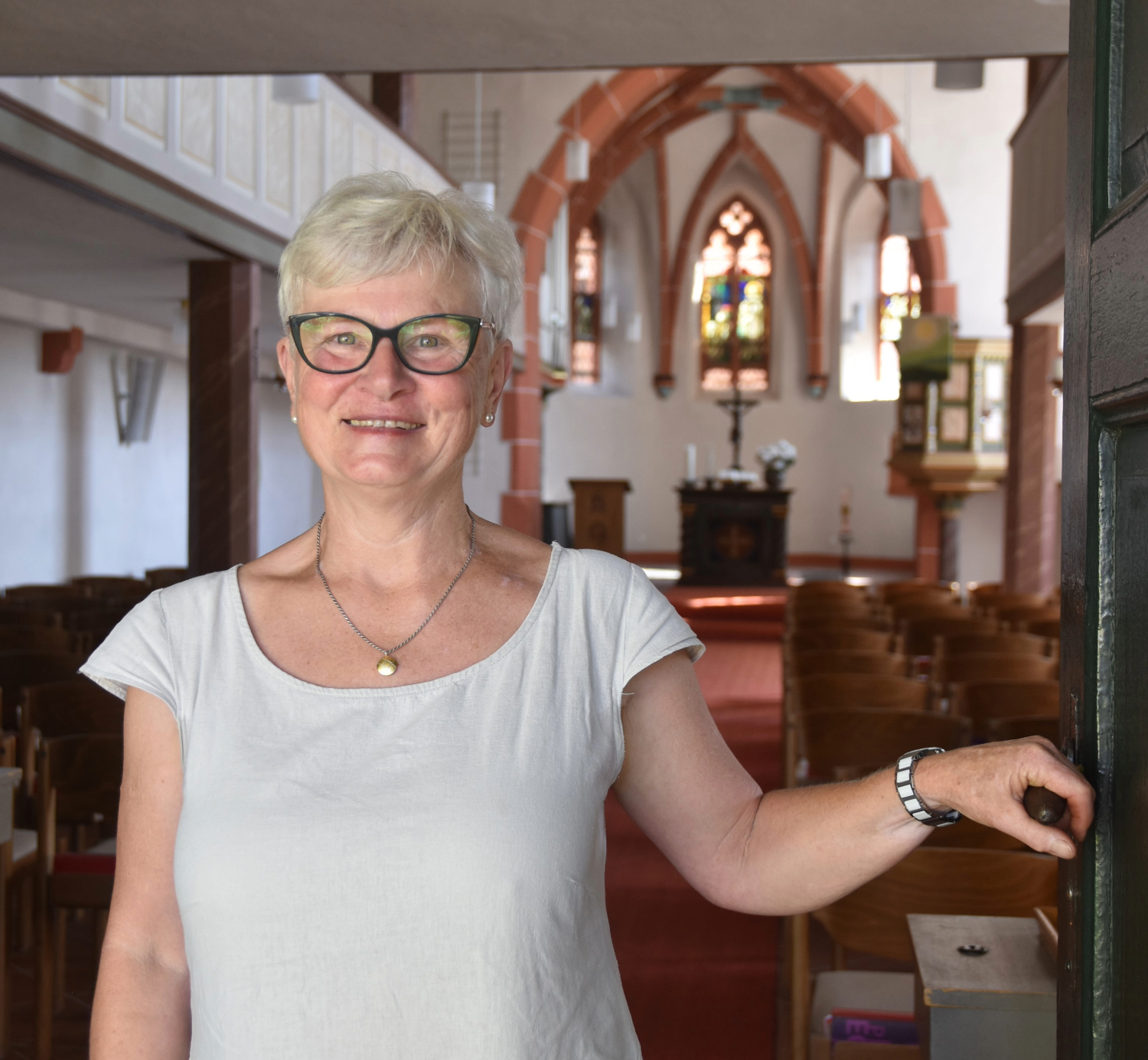Carmen Bartel steht in der Tür zur Düdelsheimer Kirche und hält die Klinke in der Hand.
