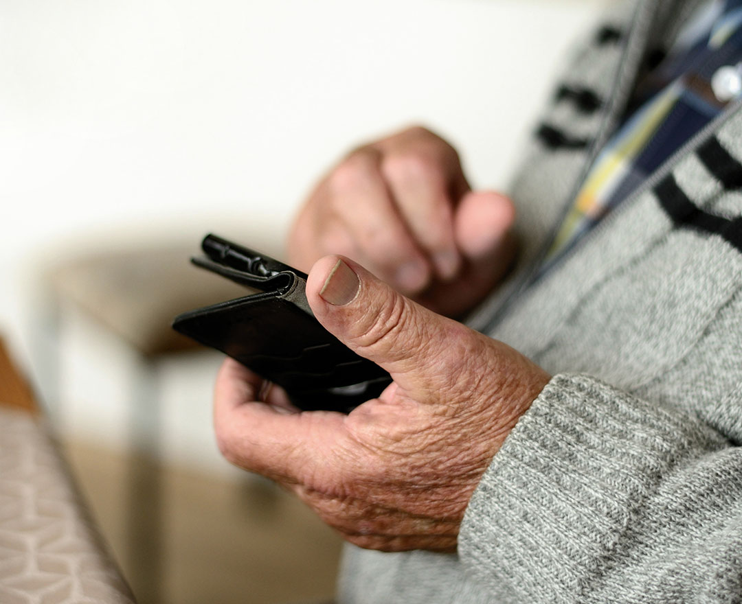 Hände eines Seniors bedienen ein Smartphone