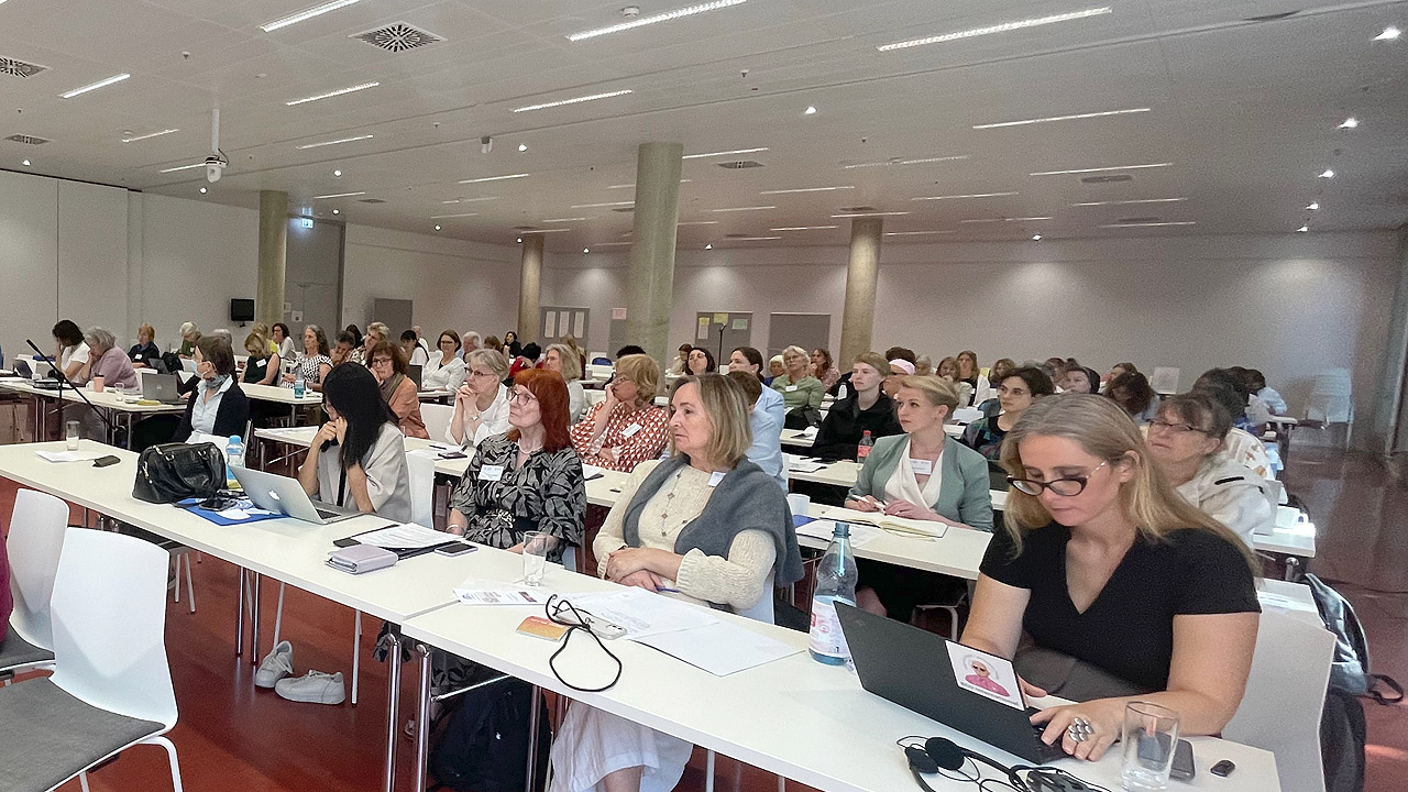 Konferenz mit Frauen an langen, weißen Tischen