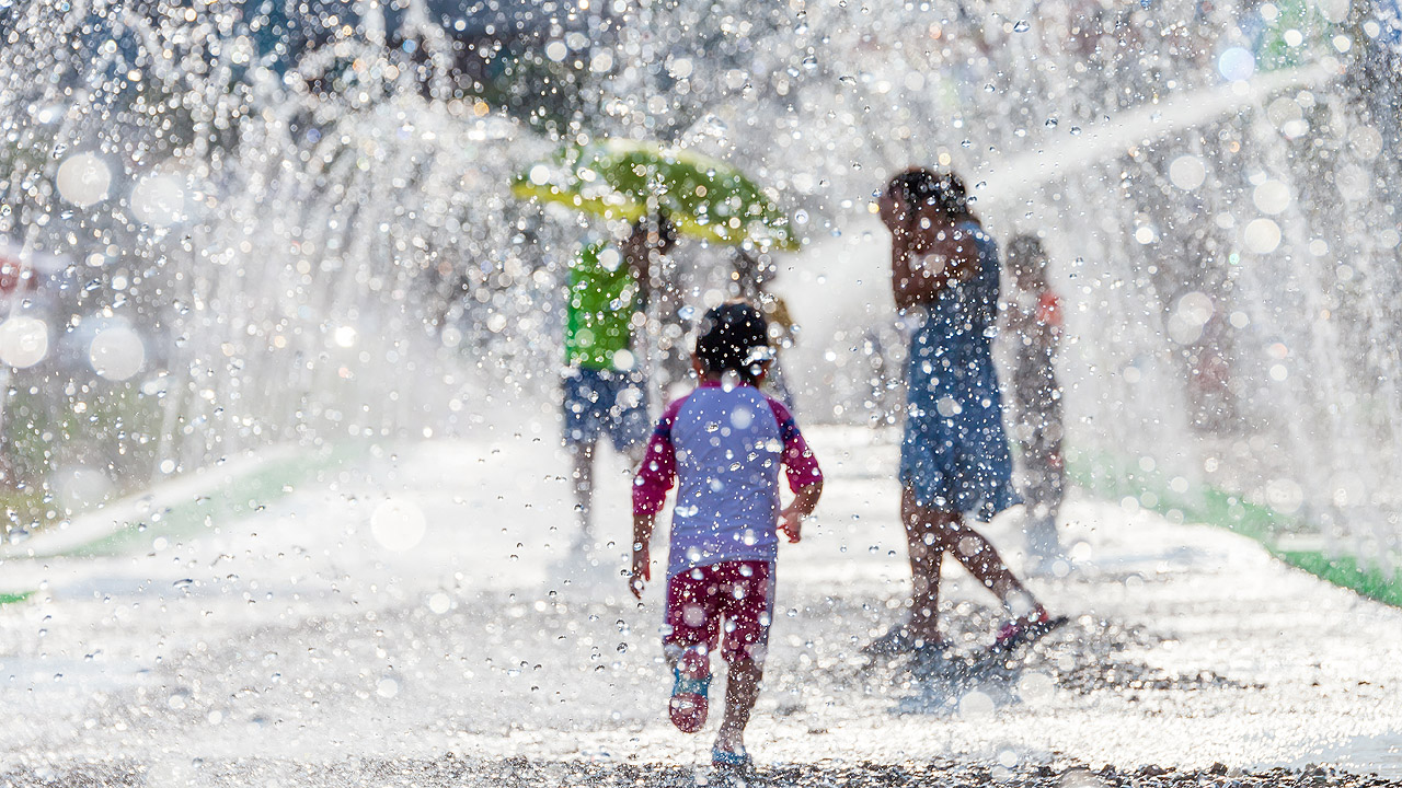 Zwei Kinder spielen in einer Springbrunnen-Anlage