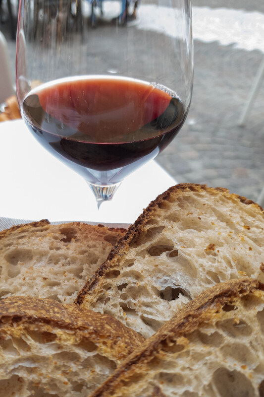 Vier Scheiben Brot und und ein Glas Wein, gefüllt mit Rotwein