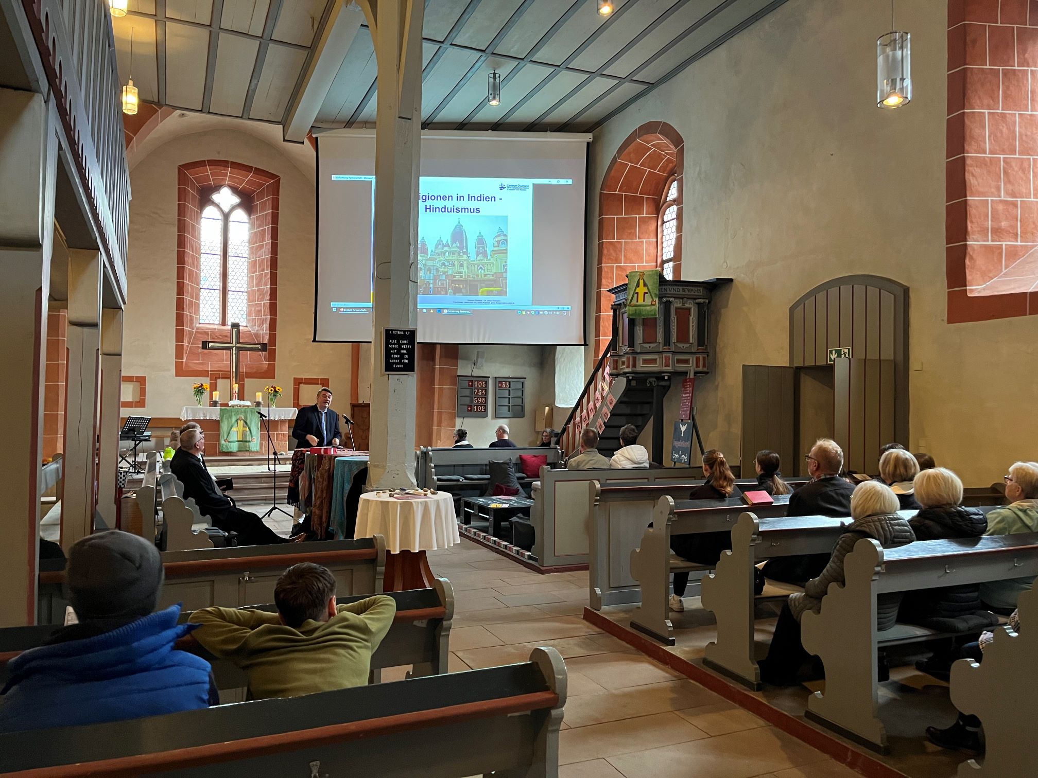 Innenraum einer Kirche, in den Bänken sitzen Besucher.