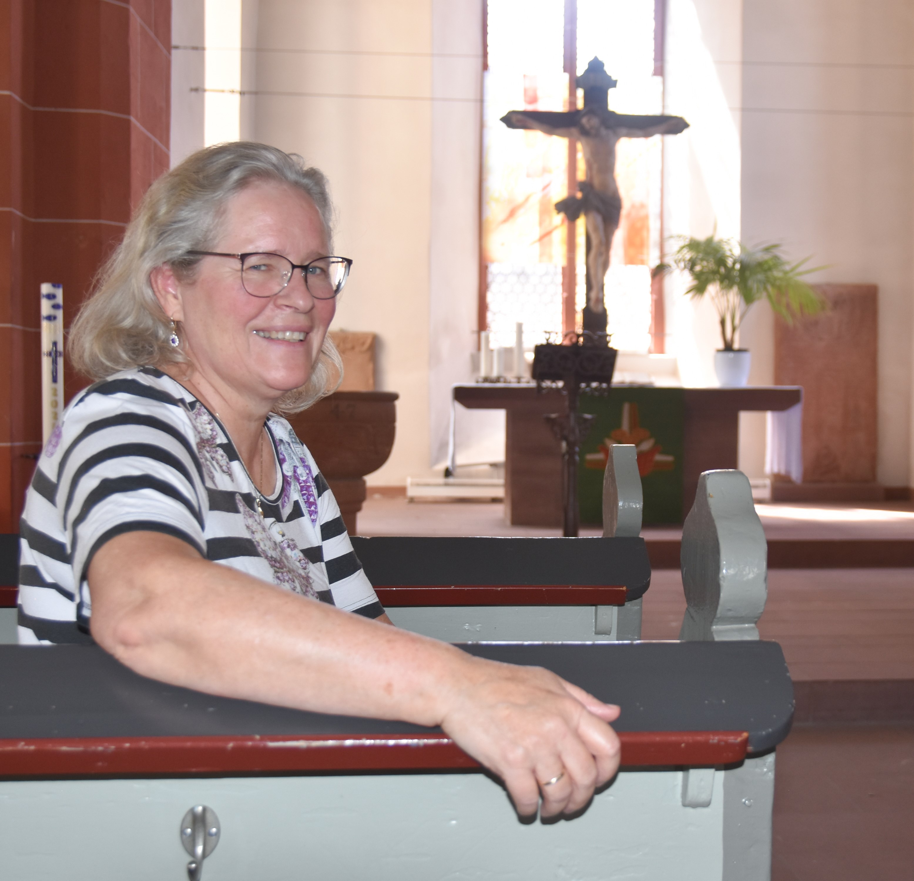 Hanne Allmansberger sitzt in einer Bank der Niddaer Stadtkirche mit dem Rücken zum Altar. Ihr rechter Arm ruht auf der Bank, sie schaut zur Kamera.