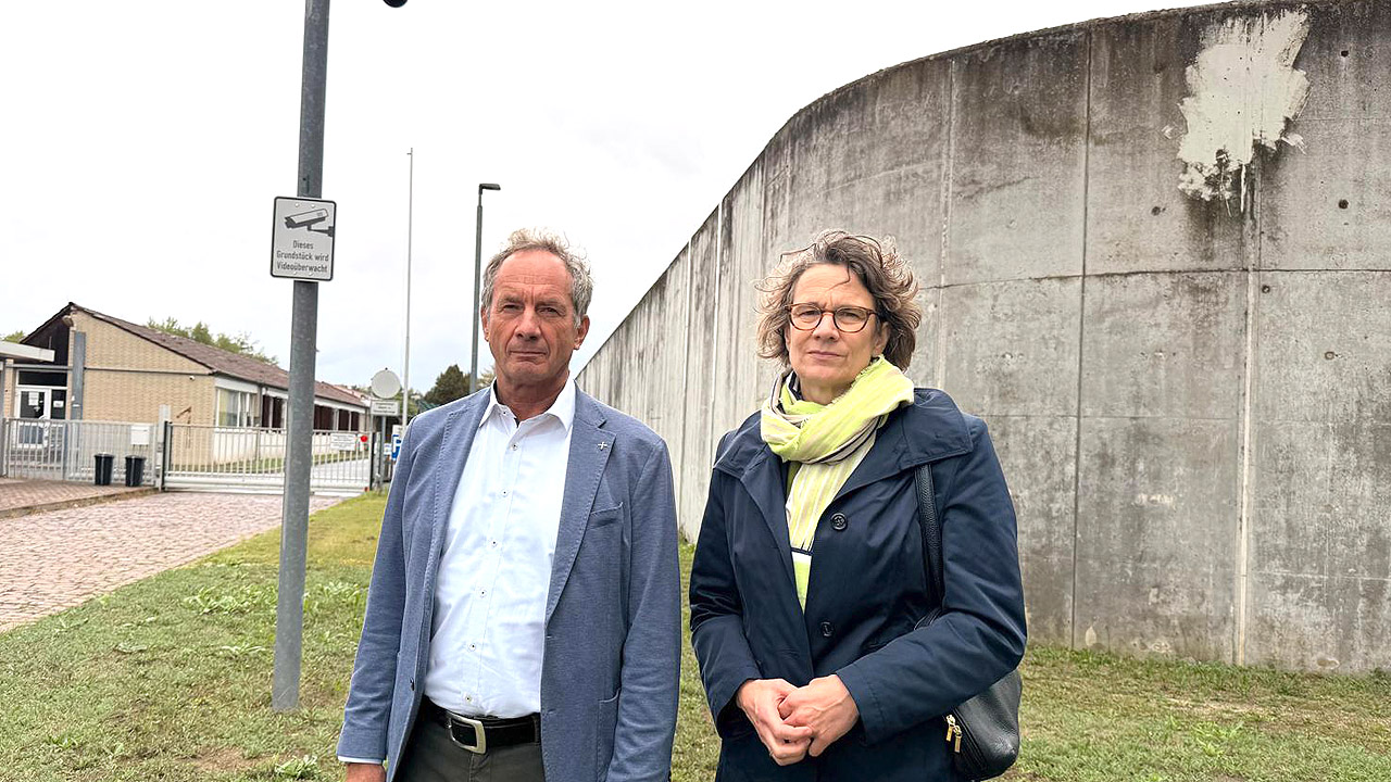 Zwei Personen vor einer grauen Mauer