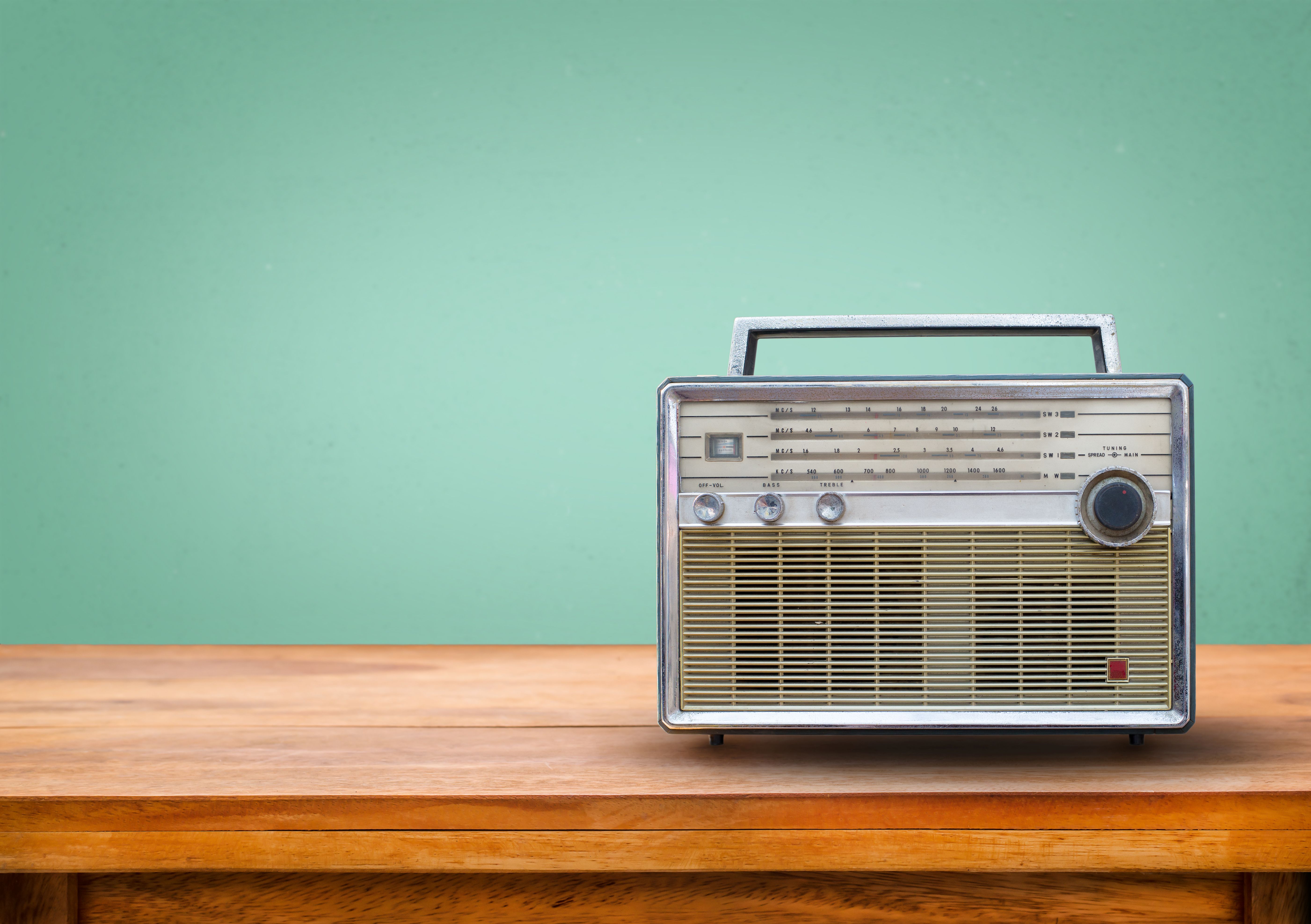 altes Radio auf einem Holzboard vor einer lindgrünen Wand