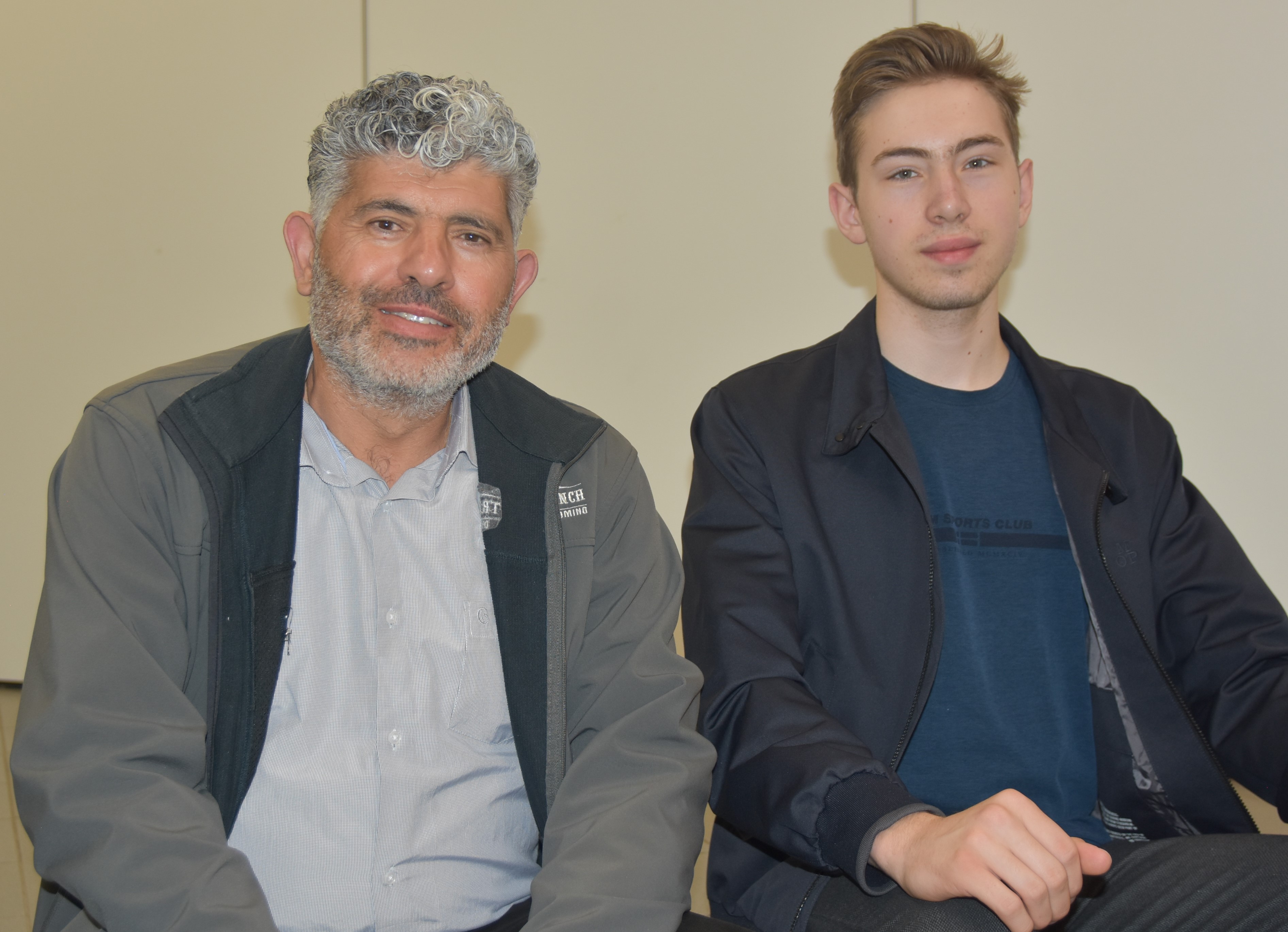 Daoud Nassar, ein Mann mit dichten grauen Locken,  und David Vinu, ein junger Mann mit kurzen Haaren, sitzen nebeneinander und schauen in die Kamera.
