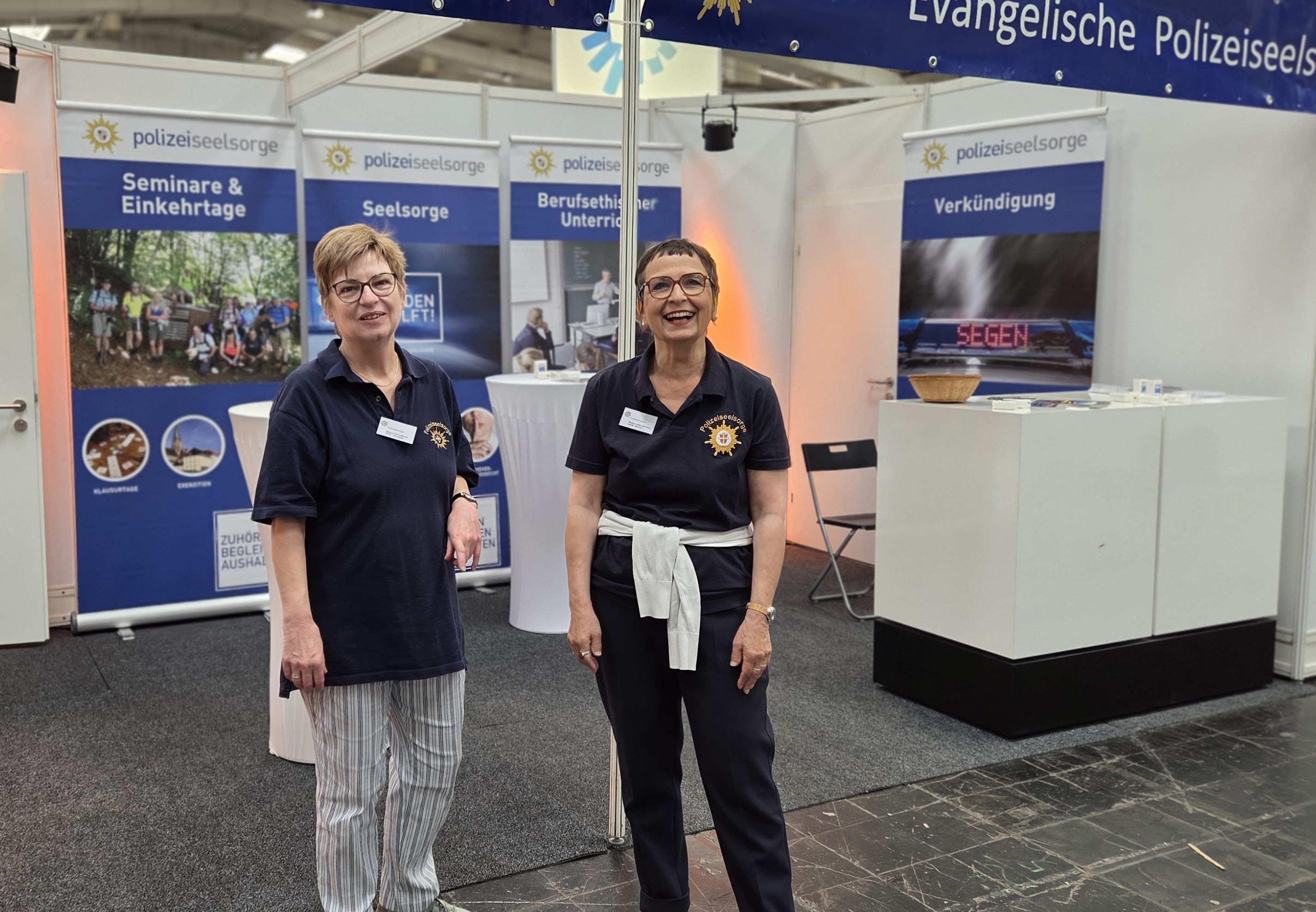 Die beiden Frauen stehen vor dem Stand der Polizeiseelsorge auf dem Markt der Möglichkeiten